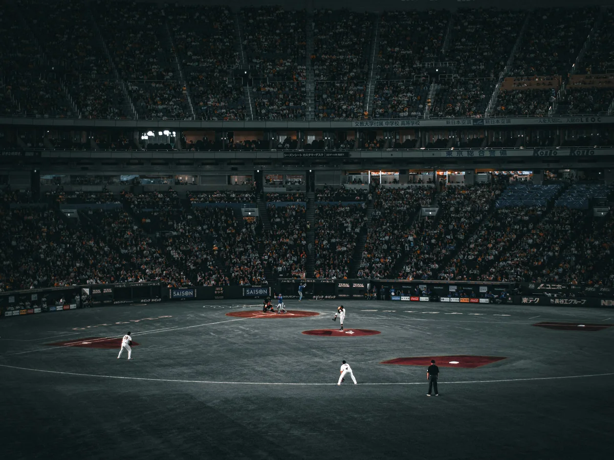 Il campo interno del Tokyo Dome e gli spalti gremiti durante una partita serale, visti da dietro la casa base