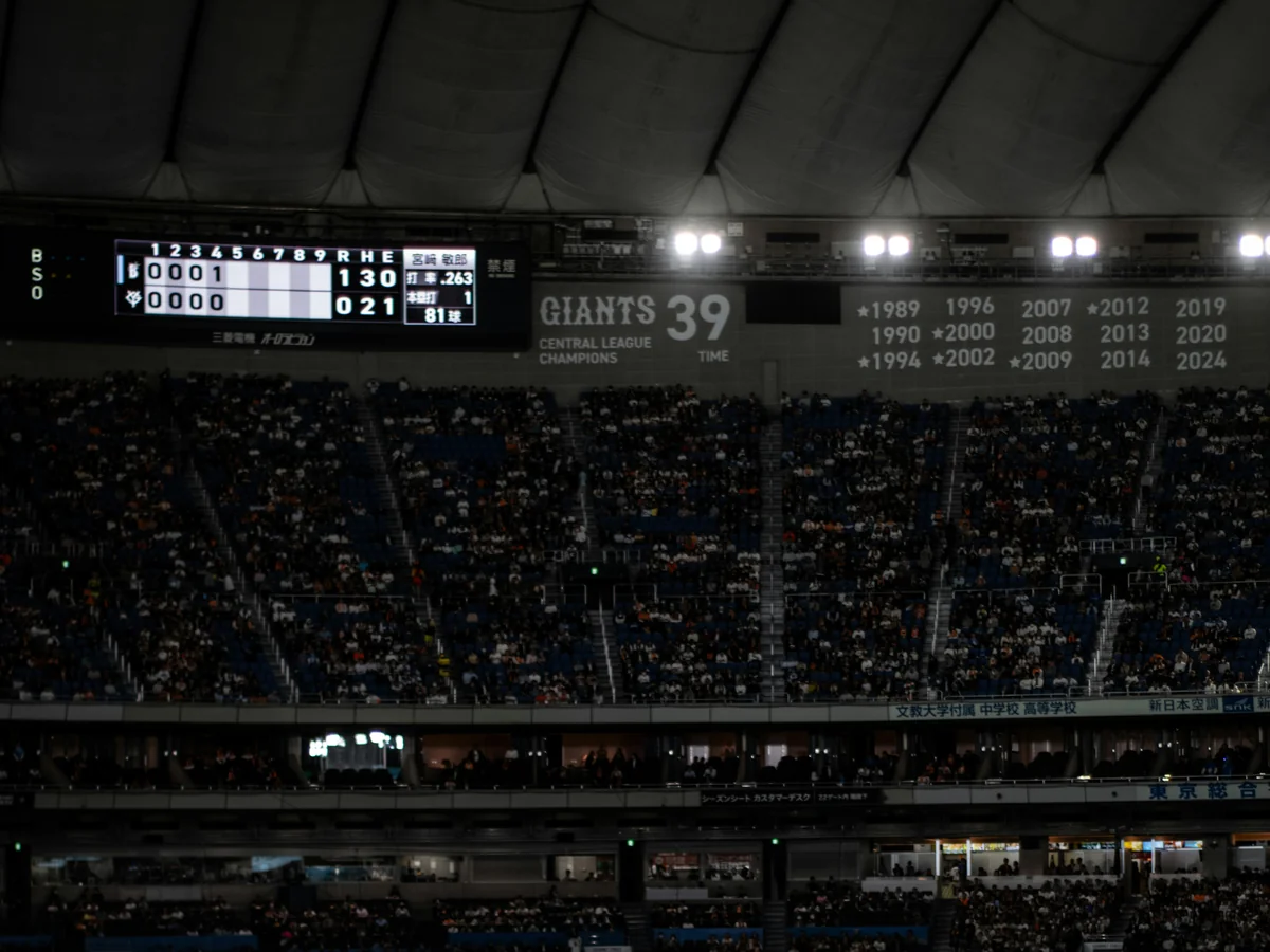 La struttura del tetto del Tokyo Dome e il tabellone dei Giants, che mostra gli anni dei campionati della Central League della squadra, sopra gli spalti gremiti durante una partita serale
